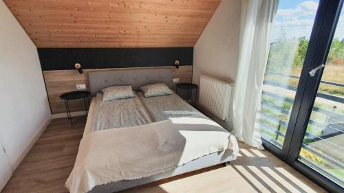 ein Schlafzimmer mit einem Bett und einem großen Fenster in der Unterkunft Domki Białe Żagle in Władysławowo