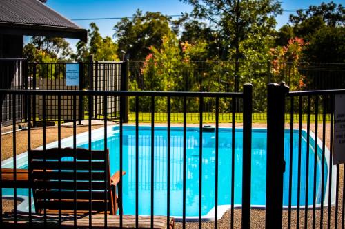 a swimming pool with two chairs next to a fence at Elfin Hill Vineyard Accommodation in Pokolbin