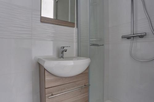 une salle de bain blanche avec un lavabo et une douche dans l'établissement Le Régent - Versailles, à Versailles