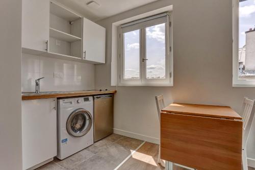 une buanderie avec une machine à laver et une fenêtre dans l'établissement Le Régent - Versailles, à Versailles