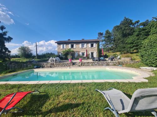 a house with a swimming pool and two lawn chairs at Cosy Room in Saint-Romain-Lachalm