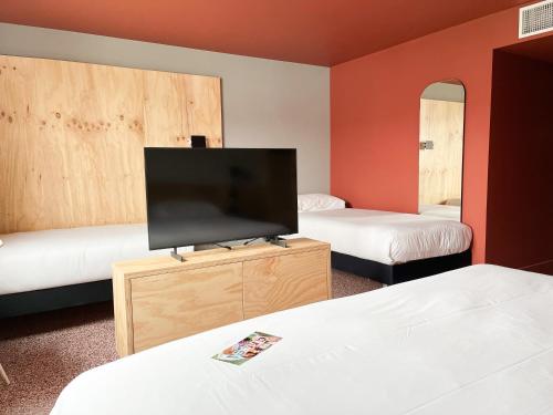 um quarto de hotel com duas camas e uma televisão de ecrã plano em Greet hôtel Montpellier Aéroport Parc des Expos em Mauguio