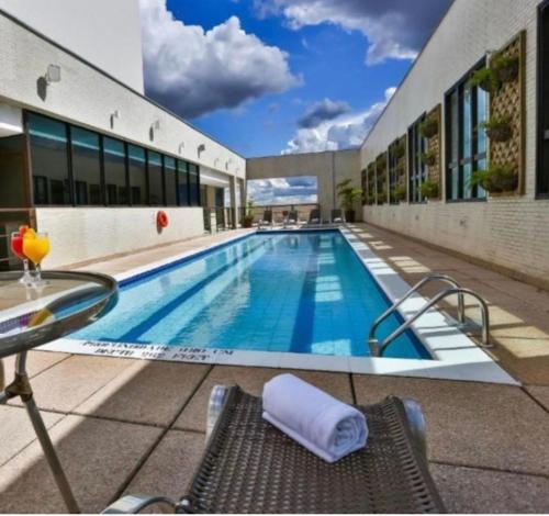 una piscina con mesa y sillas junto a un edificio en Apto no hotel Comfort de Taguatinga, en João Neiva
