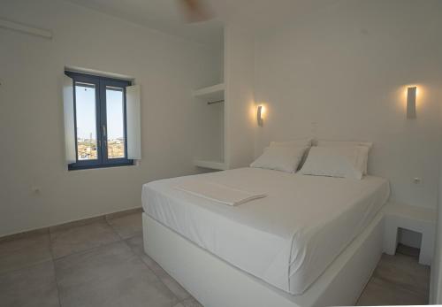 a white bedroom with a white bed and a window at Traditional White House 2 in Prodromos Paros