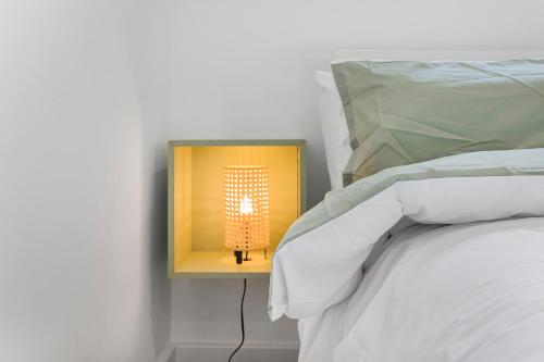 a lamp on a night stand next to a bed at London Haven at Rutland House in Ilford