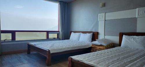 a hotel room with two beds and a window at Namhae Beach Hotel in Namhae