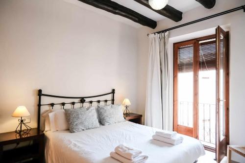 Un dormitorio con una cama blanca con toallas. en Apartamentos Cal Fuster, en Besalú