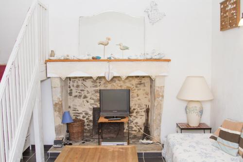 ein Wohnzimmer mit einem Kamin und einem TV in der Unterkunft Gite de la Laiterie in Bouaye