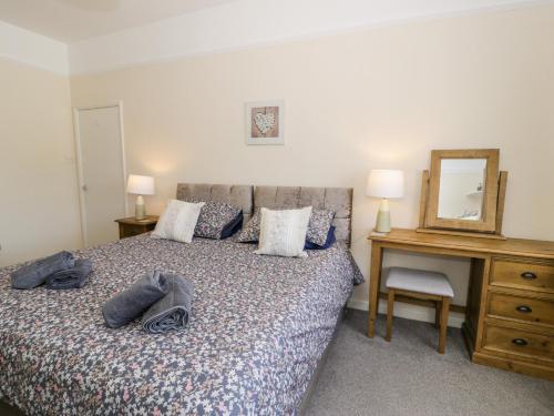 a bedroom with a bed and a desk and a mirror at Fairways in Prestatyn