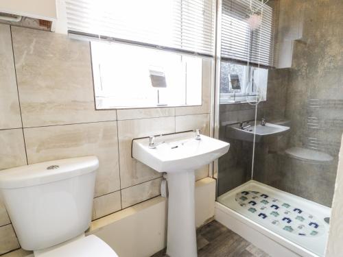 a bathroom with a toilet and a sink and a tub at Fairways in Prestatyn