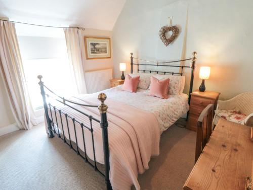 a bedroom with a large bed with pink pillows at Chapel Cottage in Ebberston