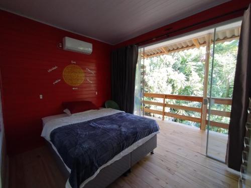 a red bedroom with a bed and a balcony at Castelo de Madeira in Blumenau