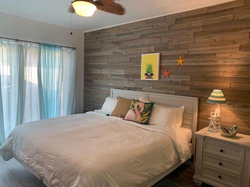 a bedroom with a bed and a wooden wall at Coastal Waikoloa Cottage Sleeps 10 in Waikoloa Village