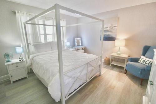 - une chambre avec un lit à baldaquin blanc et une chaise bleue dans l'établissement Coastal Village Retreat, à Jupiter