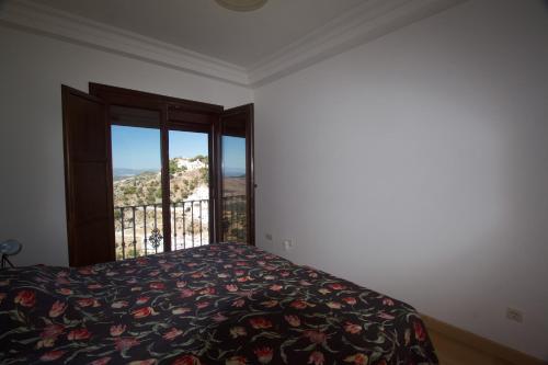 ein Schlafzimmer mit einem Bett und einem großen Fenster in der Unterkunft Casares casa in Casares