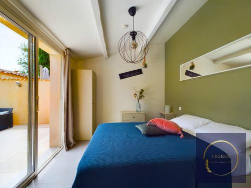 een slaapkamer met een blauw bed en een groot raam bij Le bastidon de Stéphanie Saint Rémy de Provence in Saint-Rémy-de-Provence