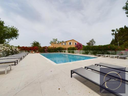 une piscine avec bancs et une maison en arrière-plan dans l'établissement Le bastidon de Stéphanie Saint Rémy de Provence, à Saint-Rémy-de-Provence
