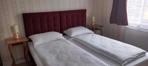 a bed with a red headboard and two pillows at Liahof in Ullared