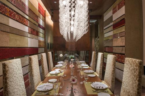 a long dining room with a long table and a chandelier at Rixos Khadisha Shymkent in Shymkent