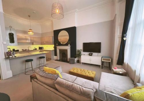 a living room with a couch and a kitchen at 3 Sheets To The Wind, Boutique Holiday Apartment in Torquay in Torquay