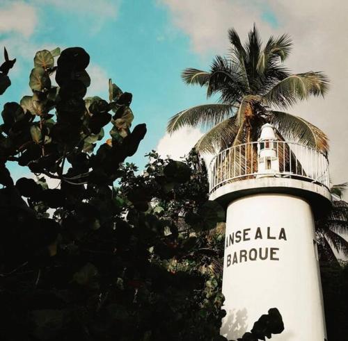 a lighthouse with a palm tree in front of it at Cocon Tropical in Vieux-Habitants