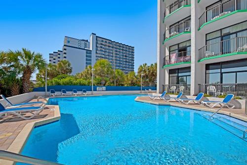 a swimming pool with lounge chairs and a building at Ocean Park Resort - Oceana Resorts Vacation Rentals in Myrtle Beach