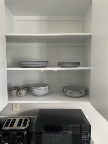 a kitchen with a microwave and plates on a shelf at Exquisite 2 Bedroom Apartment in Camrose