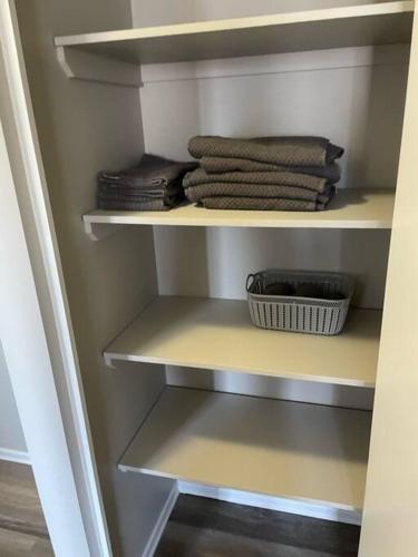 a closet with shelves with towels and a basket at Exquisite 2 Bedroom Apartment in Camrose