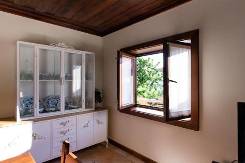 uma sala de jantar com uma janela e armários brancos em Feel Discovery Maçã Douro em Armamar