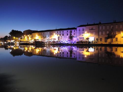 a city at night with lights reflecting in the water at L'instant romance Le Romantique in Castelnaudary