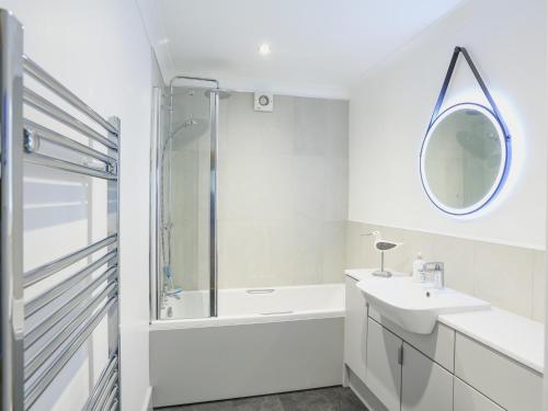 a white bathroom with a sink and a mirror at 1 Crabshell Quay in Kingsbridge