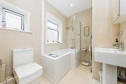 Your Chic 3BR Home Comfort and Style in London في لندن: حمام ابيض مع مرحاض ومغسلة