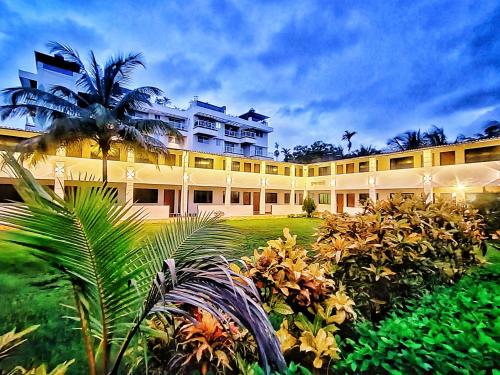 a large building with a palm tree in front of it at Opulence Beach Resort Awas, Alibaug in Alibaug