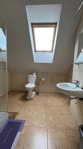 a bathroom with a toilet and a sink and a skylight at Kraken-pokoje gościnne in Krynica Morska