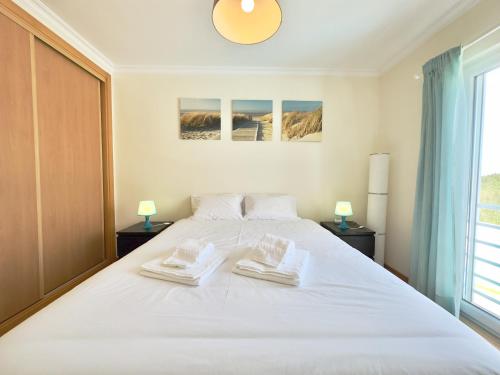 a bedroom with a large white bed with two towels on it at Baleal Happy Family Apartment in Ferrel