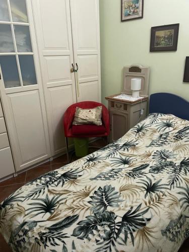 a bedroom with a bed and a red chair at B&B Villa Giardini Susanna in Gattico