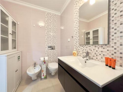 a bathroom with a sink and a toilet and a mirror at Baleal Happy Family Apartment in Ferrel