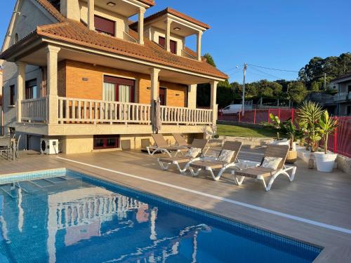 une maison avec une piscine en face d'une maison dans l'établissement VILLA CON VISTAS AL MAR, à Sanxenxo