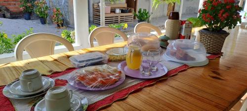 - une table en bois avec des aliments pour le petit-déjeuner et des boissons dans l'établissement Hospedaria Oliveira - Santo Amaro do Maranhão, à Queimada
