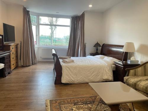 a bedroom with a bed and a couch and a window at Cosy Studio Flat at Gants Hill Station, Ilford, Essex, London in Wanstead