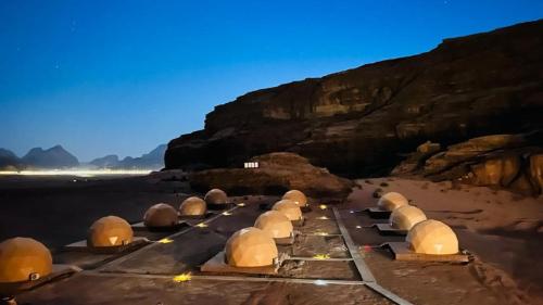 a group of domes on a beach with a mountain at Lulua luxury camp in Wadi Rum