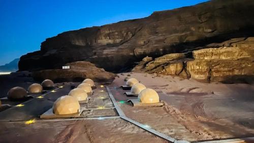 a group of domes on a beach next to a cliff at Lulua luxury camp in Wadi Rum