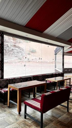 a room with a table and benches and a large window at Lulua luxury camp in Wadi Rum