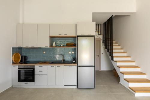 a kitchen with white cabinets and a staircase at portokoufovillas in Porto Koufo