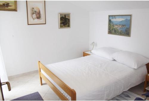 a bedroom with a white bed and two pictures on the wall at Apartments Kristina - Apartment C in Tribunj