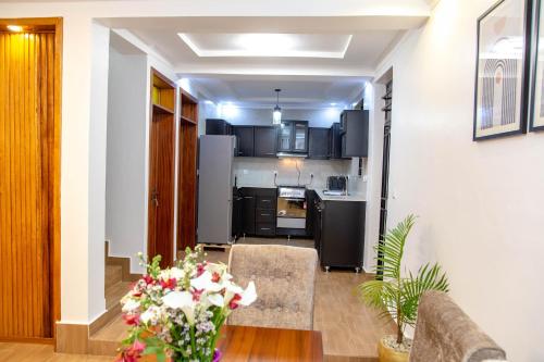 een keuken met zwarte apparatuur en een woonkamer bij Nzuri Nest Apartments Zuba in Kigali