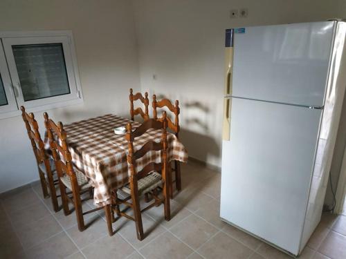 Il comprend une cuisine équipée d'une table et d'un réfrigérateur blanc. dans l'établissement Εξοχική Κατοικία - Αγιόκαμπος, à Loutra Edipsou