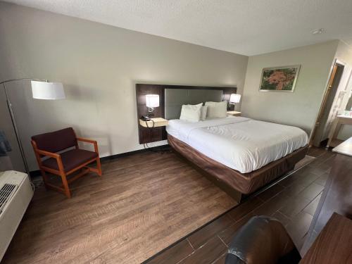 une chambre d'hôtel avec un lit et une chaise dans l'établissement Days Inn & Suites by Wyndham Monroe, à Monroe