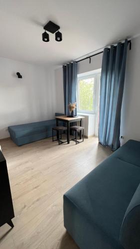 a living room with a blue couch and a table at Kraken-pokoje gościnne in Krynica Morska