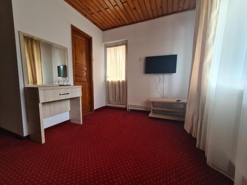 a hotel room with a television and a red carpet at Vila Vitalis in Predeal